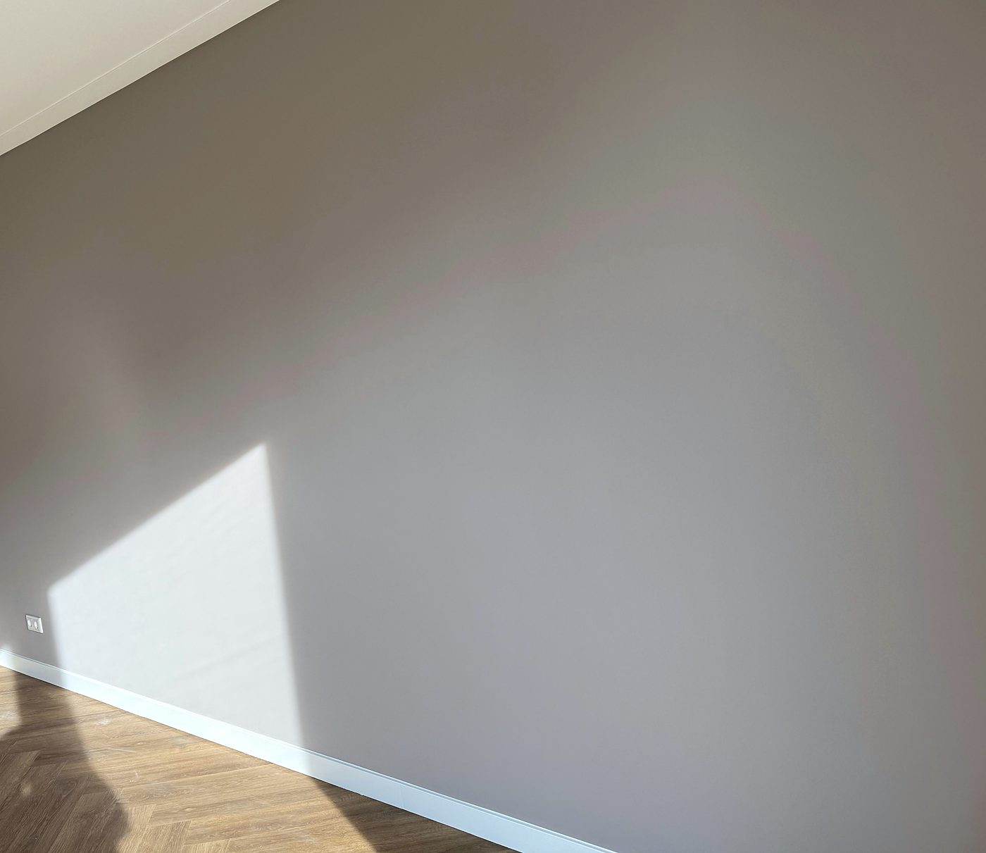 Strak geschilderde wand in warm grijs met visgraatvloer